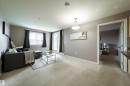 Carpeted living area featuring a sliding glass door to exterior, a window with blinds, and a permanent ceiling fixture - 115 4309 33 Street, Stony Plain, AB 