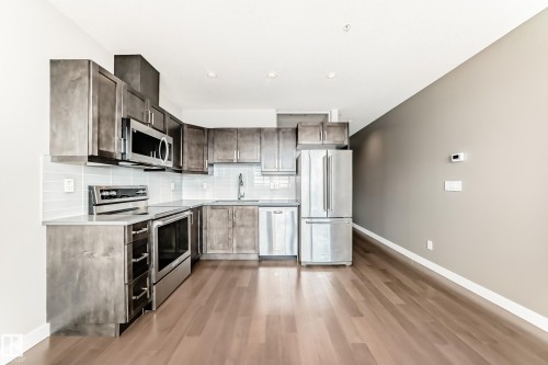 Modern kitchen featuring wood-finish cabinetry, stainless steel appliances, and wood-finish flooring - 2604 10238 103 Street, Edmonton, AB 