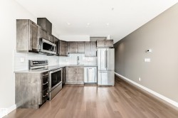 Modern kitchen featuring wood-finish cabinetry, stainless steel appliances, and wood-finish flooring - 