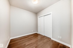 Room featuring warm wood-finish flooring, light neutral-toned walls, and bright white baseboards - 
