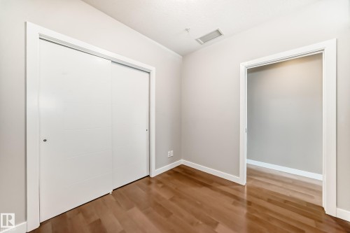 Interior room featuring wood-finish flooring, light neutral wall paint, and white baseboards - 2604 10238 103 Street, Edmonton, AB 