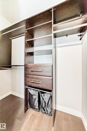 Custom closet system featuring rich wood-finish cabinetry, built-in shelving, two integrated drawers with brushed nickel hardware, and dual hanging rods - 2604 10238 103 Street, Edmonton, AB 