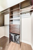 Custom closet system featuring rich wood-finish cabinetry, built-in shelving, two integrated drawers with brushed nickel hardware, and dual hanging rods - 