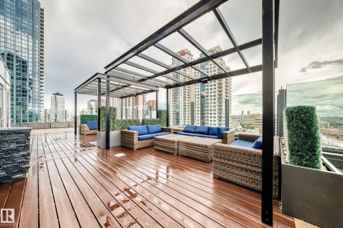 Expansive rooftop deck featuring wood-finish flooring, multiple black metal pergolas, and glass panel railings - 2604 10238 103 Street, Edmonton, AB 
