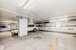 Underground parking garage featuring concrete flooring, overhead fluorescent lighting, and numbered parking stalls - 