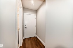 Entryway featuring wood-finish flooring, a white paneled door with contemporary hardware, and recessed lighting - 