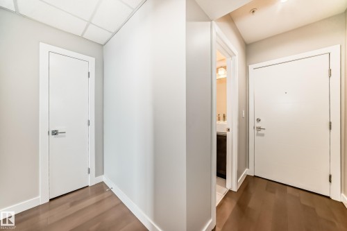 Hallway featuring wood-finish flooring, crisp white doors, and contemporary hardware - 2604 10238 103 Street, Edmonton, AB 