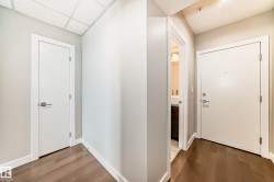 Hallway featuring wood-finish flooring, crisp white doors, and contemporary hardware - 
