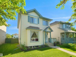 Two-story residence featuring light-colored siding with contrasting teal trim, a covered front entry, and a bay window - 