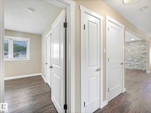 Interior hallway with wood-finish flooring, light neutral wall paint, and white trim - 12241 54 Street, Edmonton, AB 
