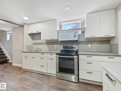 Contemporary kitchen featuring white cabinetry, stainless steel range and microwave, light-toned countertops, and a gray-toned tile backsplash - 