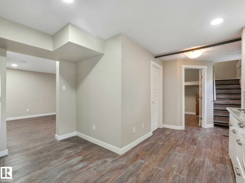 Spacious interior featuring wood-finish flooring, light neutral wall tones, recessed lighting, and white trim - 12241 54 Street, Edmonton, AB 