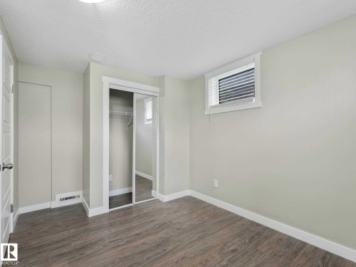 Bright room featuring light wood-finish flooring, a mirrored closet with sliding doors, white trim, and a window with blinds - 12241 54 Street, Edmonton, AB 