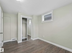 Bright room featuring light wood-finish flooring, a mirrored closet with sliding doors, white trim, and a window with blinds - 