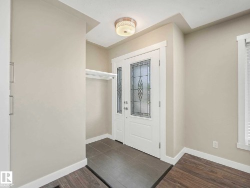 Entryway featuring a white door with decorative leaded glass, tile flooring, and a built-in coat rack - 12241 54 Street, Edmonton, AB 
