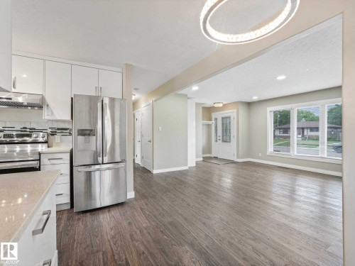 Open-concept living space featuring wood-finish flooring, a modern chandelier, and recessed lighting - 12241 54 Street, Edmonton, AB 