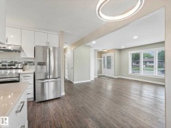 Open-concept living space featuring wood-finish flooring, a modern chandelier, and recessed lighting - 