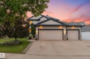 Exterior featuring light-toned siding with dark trim, a dual garage, and a concrete driveway - 18 Woodbend Way, Fort Saskatchewan, AB 