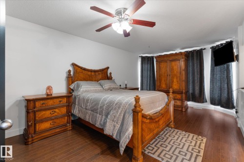 Spacious room featuring wood-finish flooring, a ceiling fan with integrated lighting, and multiple windows - 18 Woodbend Way, Fort Saskatchewan, AB 