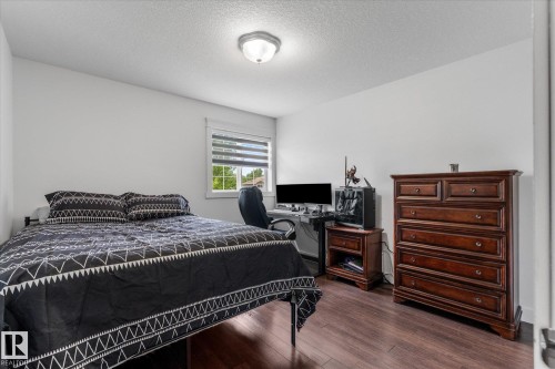 Bedroom featuring wood-finish flooring, a window with horizontal blinds, and a flush mount ceiling light fixture - 18 Woodbend Way, Fort Saskatchewan, AB 