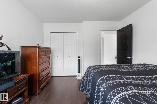 Wood-finish flooring throughout, bright white walls, and a multi-panel bifold closet door - 18 Woodbend Way, Fort Saskatchewan, AB 