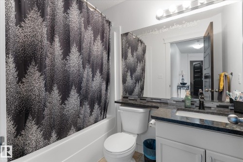 Bathroom featuring a white bathtub, toilet, and a vanity with a dark countertop and undermount sink - 18 Woodbend Way, Fort Saskatchewan, AB 