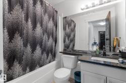Bathroom featuring a white bathtub, toilet, and a vanity with a dark countertop and undermount sink - 