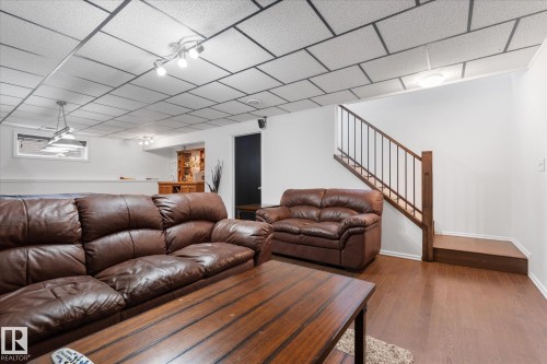 Finished lower level featuring wood-finish flooring, white walls, and a drop ceiling with integrated lighting - 18 Woodbend Way, Fort Saskatchewan, AB 