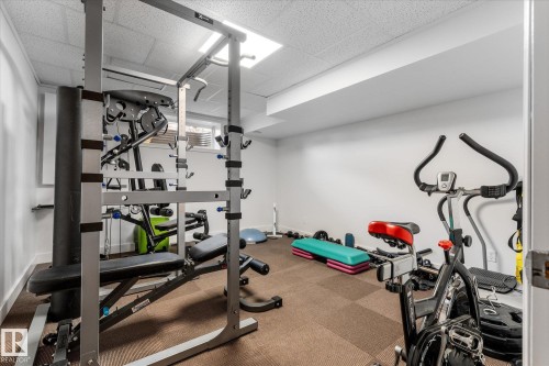 Dedicated exercise room featuring soft tile flooring, recessed lighting, white walls, and a window for natural light - 18 Woodbend Way, Fort Saskatchewan, AB 