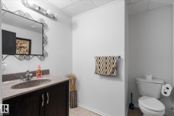 Vanity area featuring a dark wood-finish cabinet with silver-tone pulls, a built-in sink, and a light-toned countertop - 