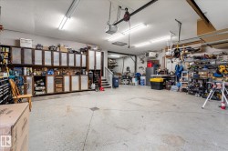 Expansive garage space featuring a concrete floor, extensive built-in cabinetry with wood-finish frames and textured panel inserts, and overhead fluorescent lighting fixtures - 