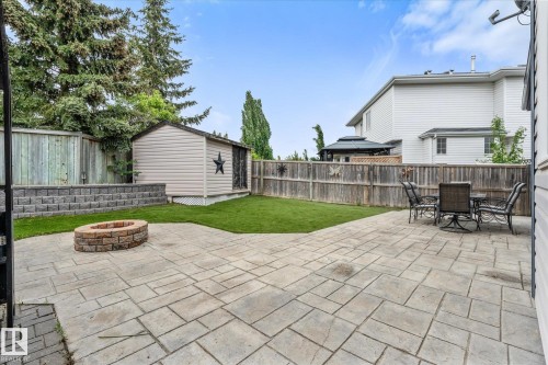 Expansive stamped concrete patio featuring a built-in stone fire pit - 18 Woodbend Way, Fort Saskatchewan, AB 
