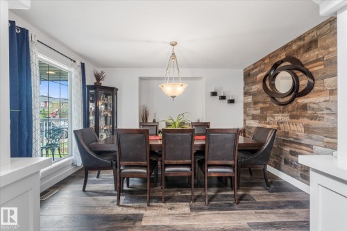 Dining area with wood-finish flooring, a feature wall with horizontal wood paneling, and an overhead chandelier - 18 Woodbend Way, Fort Saskatchewan, AB 