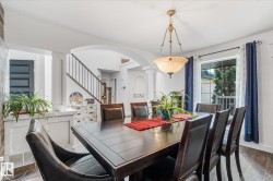 Spacious dining area featuring dark wood-finish flooring, a contemporary chandelier, and a large window - 