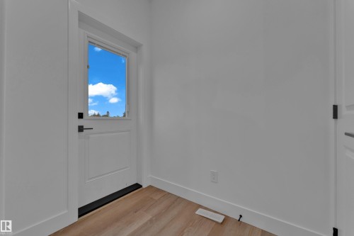 White paneled door with upper glass pane, featuring a matte black lever handle - 4213 63 Street, Beaumont, AB 