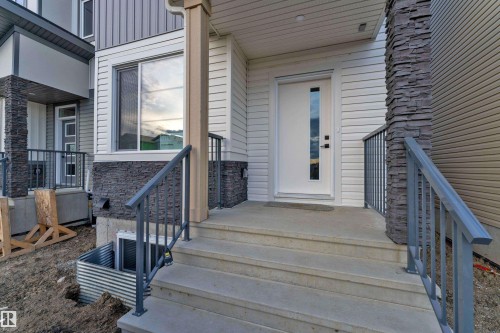 Modern exterior with a white entry door featuring a vertical glass insert - 4213 63 Street, Beaumont, AB 