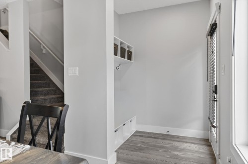 Entryway featuring wood-finish flooring, a built-in bench with storage, overhead shelving, and a coat hook - 17733 64A Street, Edmonton, AB 