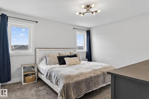 Bedroom featuring neutral wall paint, two windows with white trim, and a modern ceiling light fixture - 17733 64A Street, Edmonton, AB 