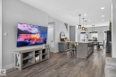 Open-concept living area featuring wood-finish flooring, a kitchen island with integrated appliances, pendant lighting, and recessed ceiling lights - 17733 64A Street, Edmonton, AB 