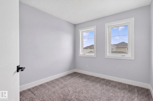 Neutral-toned room featuring two framed windows, plush gray carpeting, and white baseboards - 17733 64A Street, Edmonton, AB 