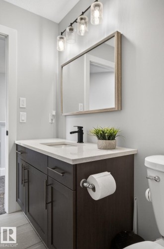 Vanity featuring a white countertop with an undermount sink, matte black faucet, and dark wood-finish cabinetry with bar pulls - 17733 64A Street, Edmonton, AB 