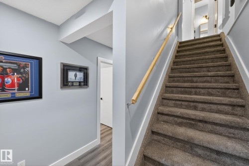 Carpeted staircase with a light wood handrail, light gray walls, and white baseboards - 17733 64A Street, Edmonton, AB 