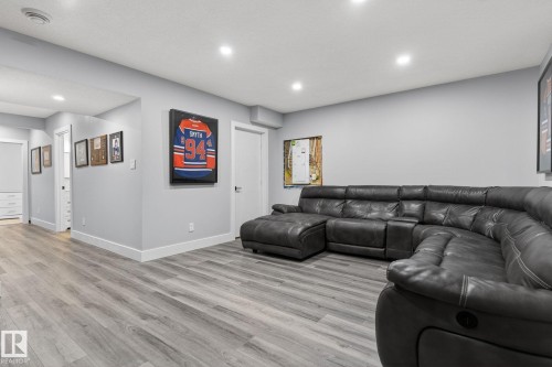Spacious recreation room featuring recessed lighting, light gray walls, white trim, and wood-finish flooring - 17733 64A Street, Edmonton, AB 