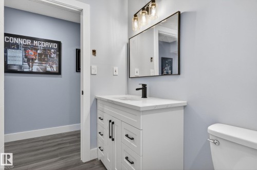 Bathroom vanity featuring a white shaker-style cabinet, a white countertop, and a matte black faucet - 17733 64A Street, Edmonton, AB 