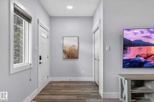 Entryway featuring wood-finish flooring, light gray walls, a white paneled door with transom windows, and white trim - 17733 64A Street, Edmonton, AB 