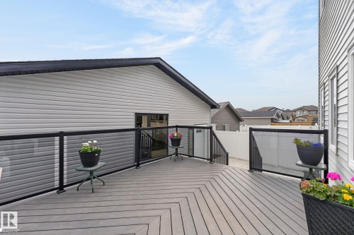 Multi-level composite deck featuring glass panel railings with dark frames, a private entry, and a perimeter fence - 17733 64A Street, Edmonton, AB 
