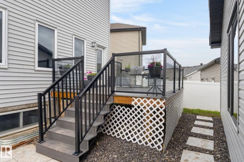 Elevated deck with black metal and glass railing, accessed by composite steps with matching black metal handrails - 17733 64A Street, Edmonton, AB 