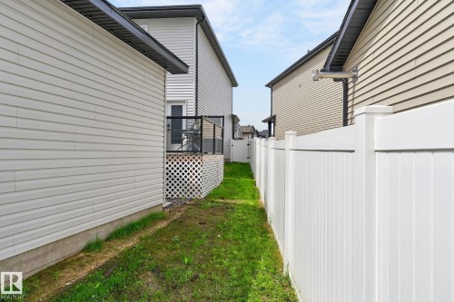 Exterior side yard featuring a white privacy fence, a wooden deck with black railings, and white lattice skirting - 17733 64A Street, Edmonton, AB 