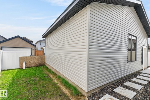 Detached garage with horizontal siding, a black shingle roof, and dark-framed windows - 17733 64A Street, Edmonton, AB 