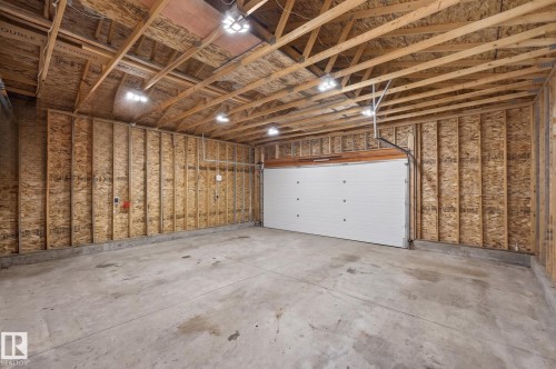 Spacious garage featuring exposed wood framing, a concrete floor, and multiple overhead light fixtures - 17733 64A Street, Edmonton, AB 